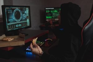 man in black hoodie eating his snack in front of the computer
